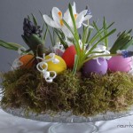 Osterkranz aus Moos mit bunten Eiern und Fruehlingsblumen