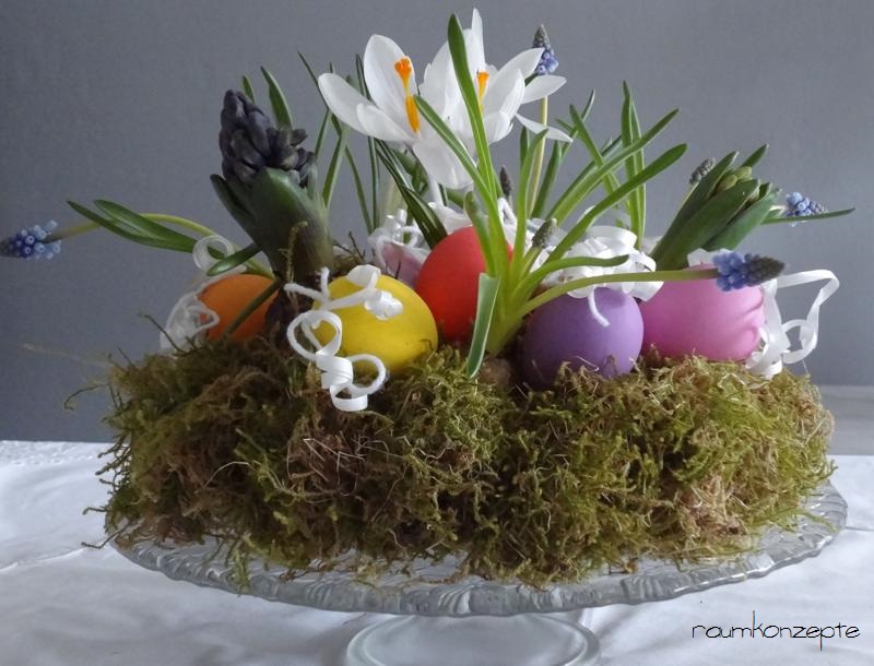 Osterkranz aus Moos mit bunten Eiern und Fruehlingsblumen