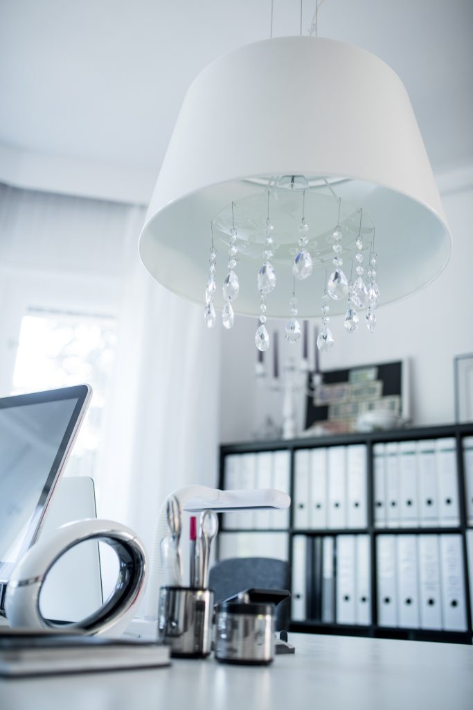 Ein Arbeitszimmer in Pink mit weißem Arbeitstisch, Lampe und Ordnern und schwarzem Ordnerregal