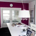 Ein Arbeitszimmer in Pink mit weißem Arbeitstisch und Lampe vor pinkfarbener Wand mit geschlossener Schiebetür