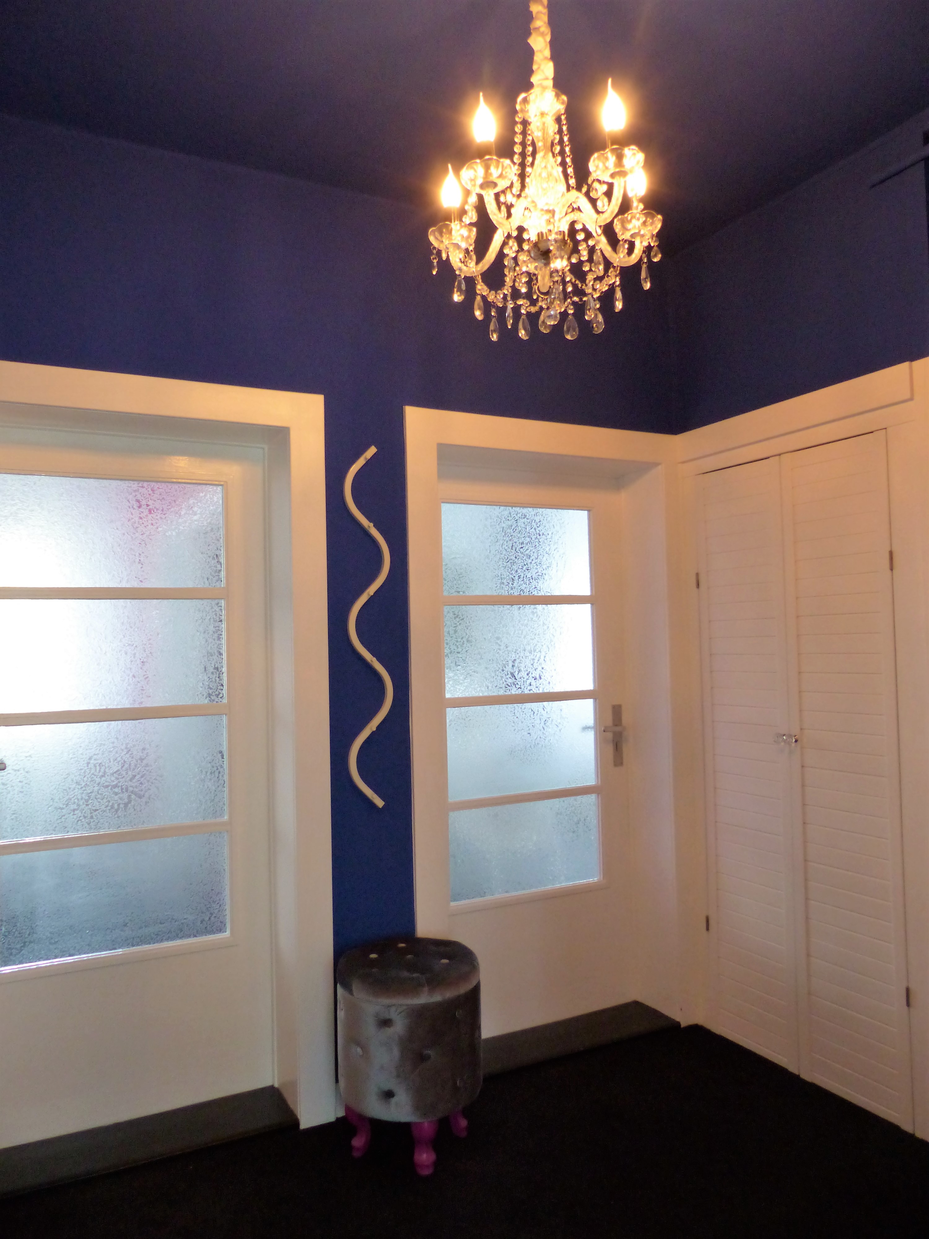 kleiner blauer Innen-Flur mit Glastüren und Wandschrank in Abendstimmung