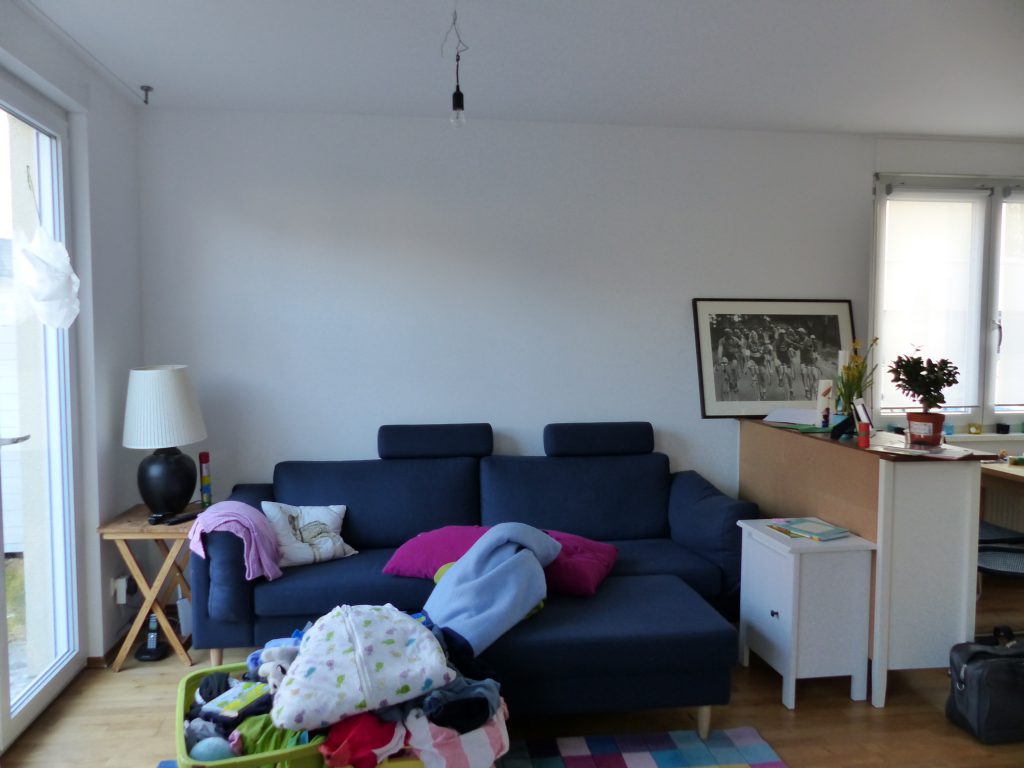 angezogenes Wohnzimmer vor Umgestaltung mit ungünstig plaziertem blauen Sofa