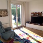 angezogenes Wohnzimmer nach Umgestaltung mit blauem Sessel und freiem Durchgang zur Terrasse