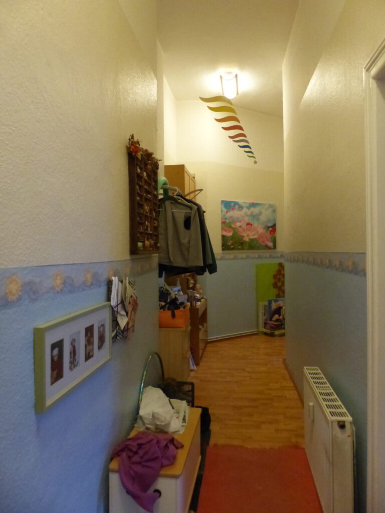 Flur Blick 6 vorher mit Garderobe, Heizkoerper und Waenden in hellblau und beige