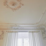 weisse Vorhaenge unter Stuckdecke mit Mittelrosette