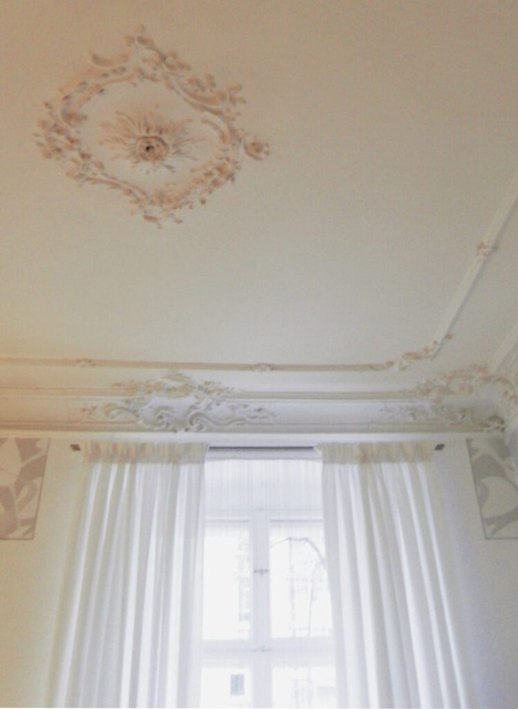 weisse Vorhaenge unter Stuckdecke mit Mittelrosette