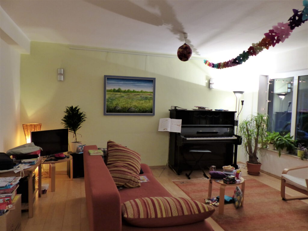 altes Klavier vor Umgestaltung mit altem Sofa und Wandbild vor gelber Wand