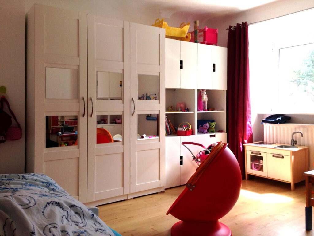Kinderzimmer links nach Umgestaltung aufraeumbar mit großen weissen Schraenken und neuen Vorhaengen