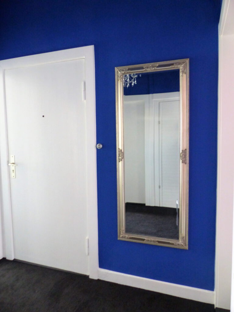 kleiner blauer Innen-Flur mit Wand neben Eingangstür nach Renovierung