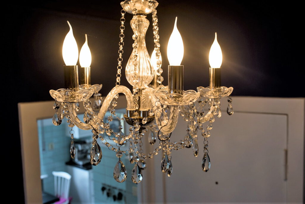 kleiner blauer Innen-Flur mit Kristall-Leuchter vor Wohnungstür und Küche