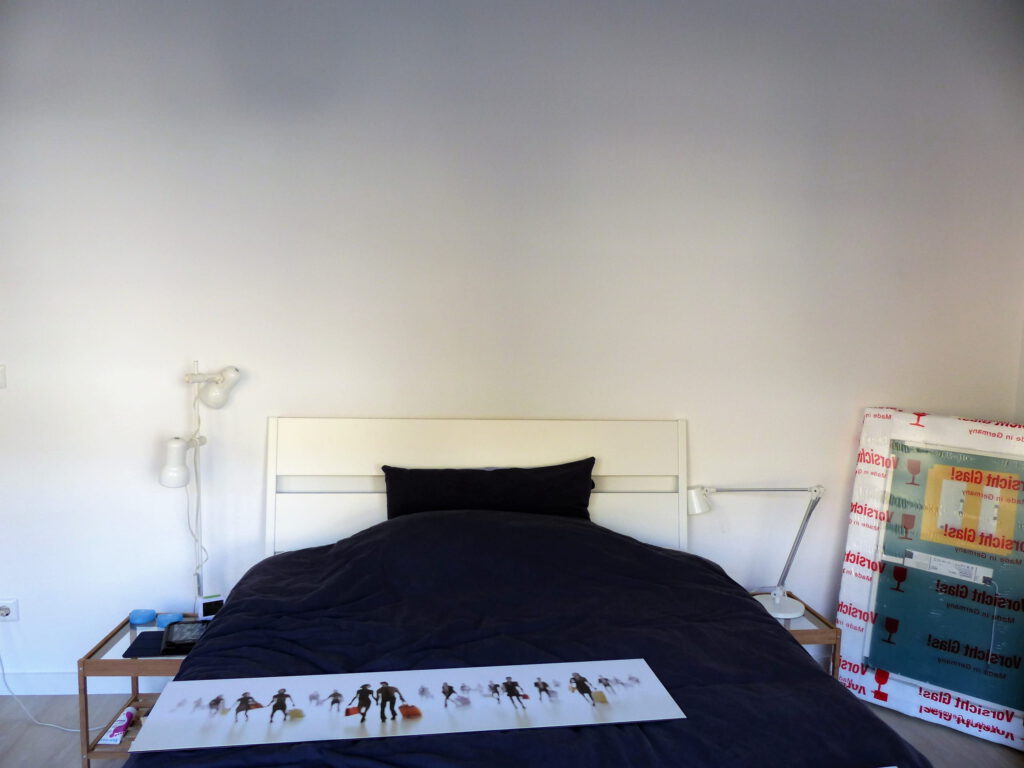 Schlafzimmer Blick 15 vorher mit Bett, blauem Bettzeug, Glastischen und weissen Lampen