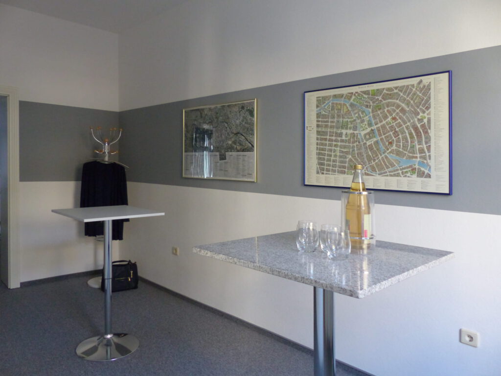 Schulungsraum nach Umgestaltung mit weißer Wand und grauem Farbstreifen über Stehtische