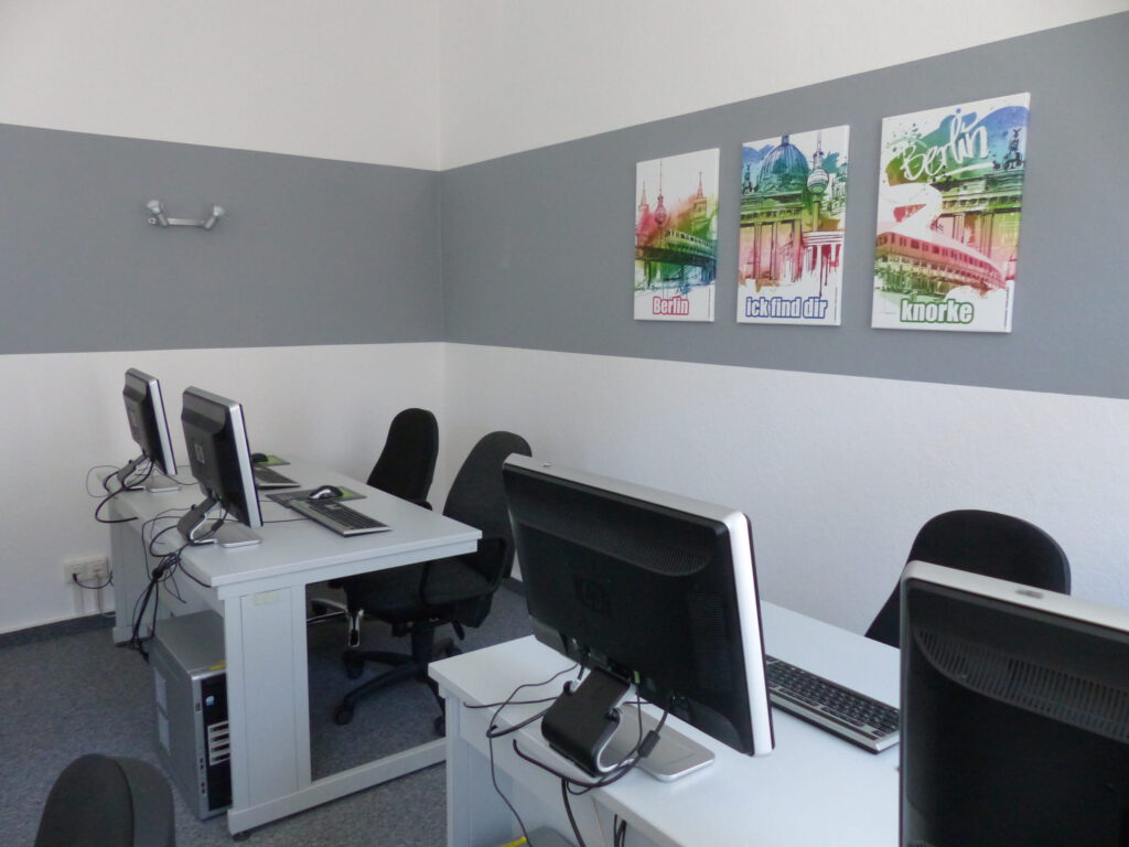 Schulungsraum nach Umgestaltung Rückseite mit weißer Wand und grauem Farbstreifen als Rahmen für drei Wandbilder