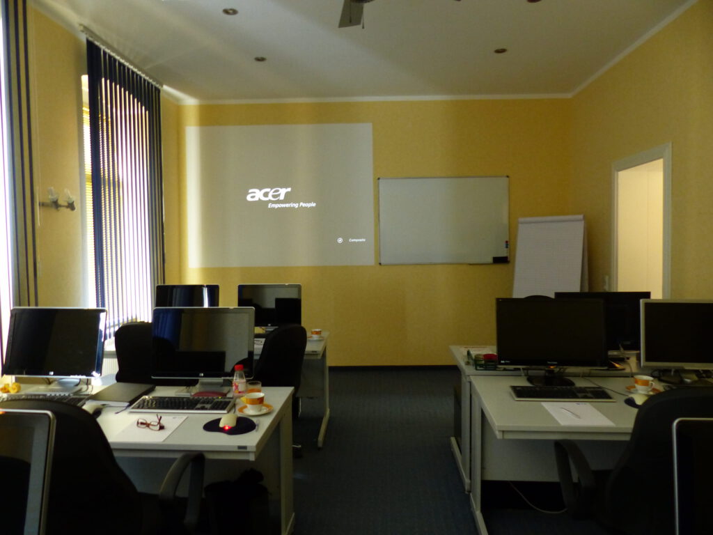 Schulungsraum vor Umgestaltung Vorderseite mit weißer Präsentationsfläche vor gelber Wand