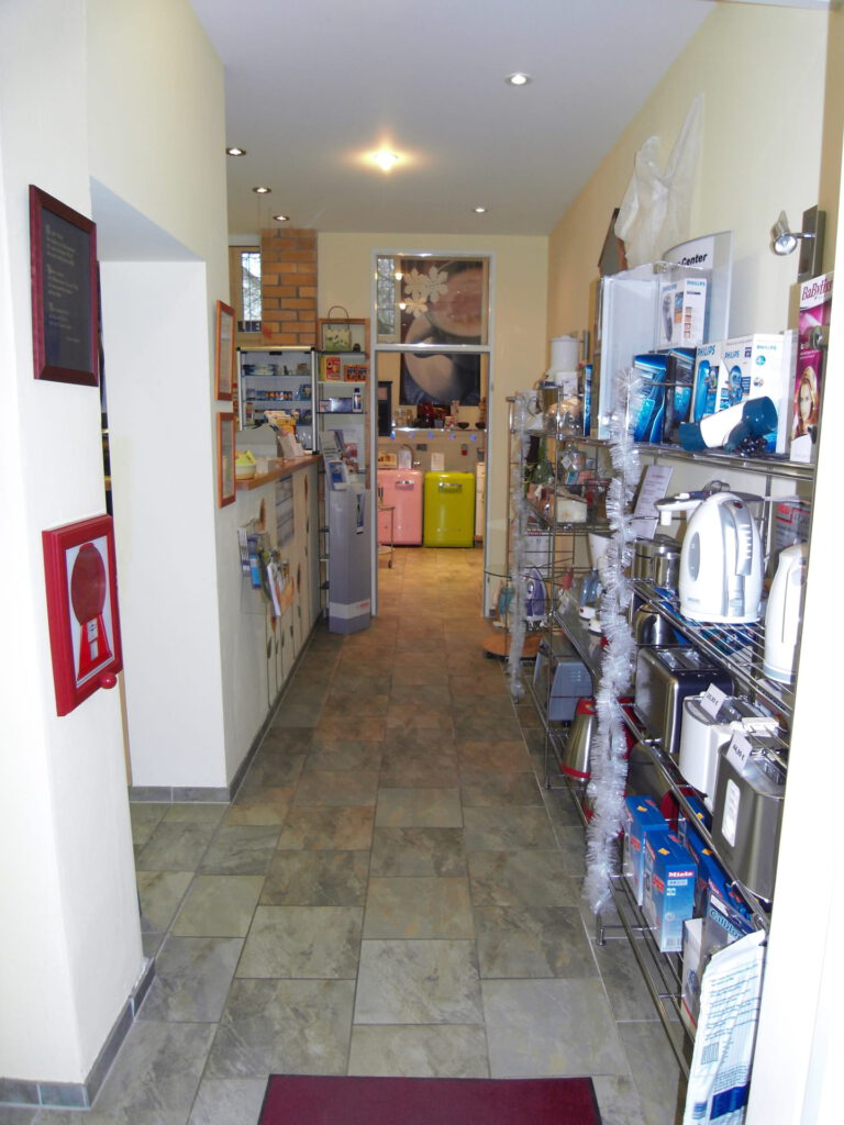 Verkaufsraum Eingang vorher mit sehr vielen Waren im Regal