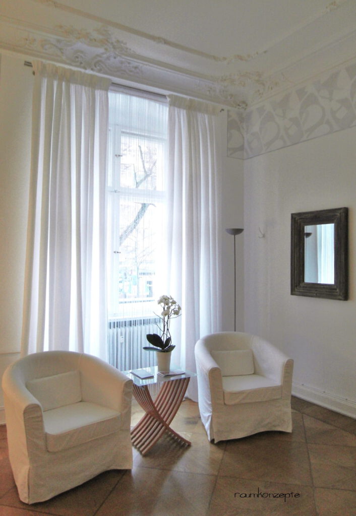 weisse Vorhänge vor Sitzplatz mit 2 Sesseln und Beistelltisch