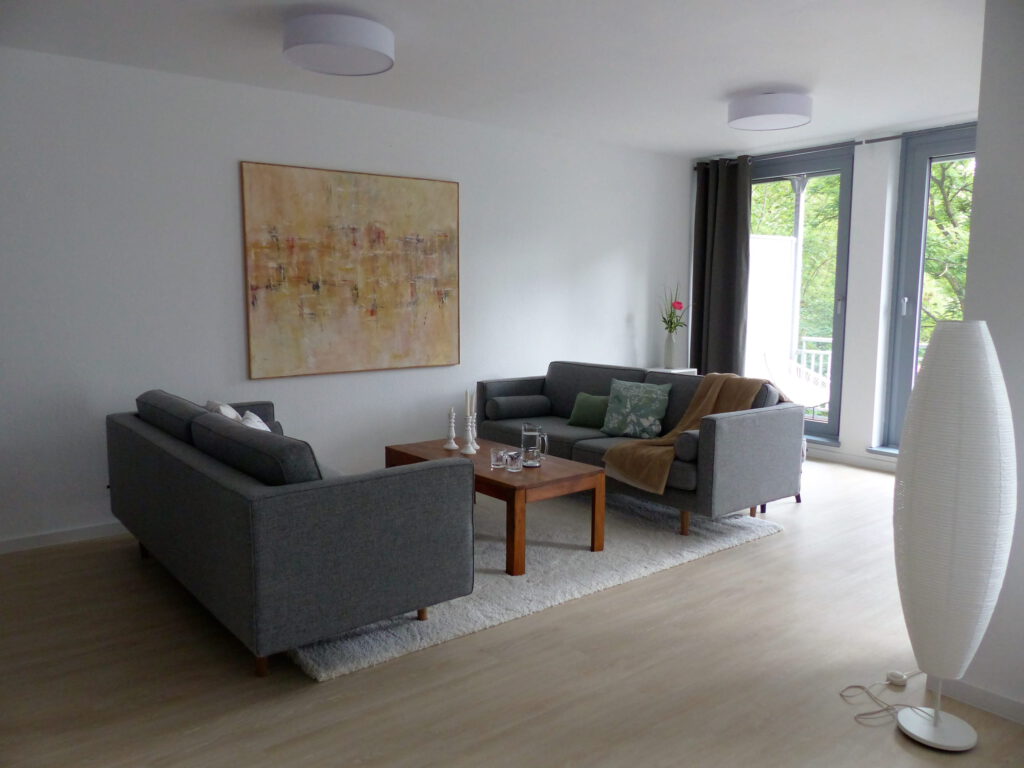 Wohnbereich Blick 6 nachher mit Zweisitzer, Couchtisch, Wandbild, Teppich und Stehlampe
