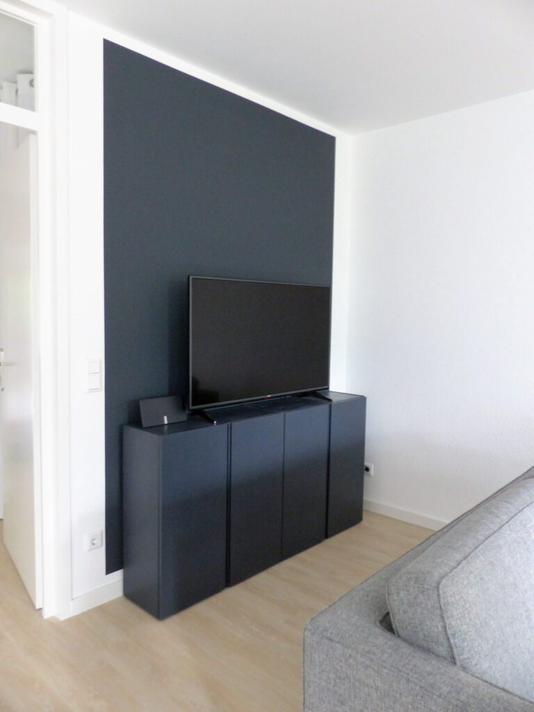 Wohnbereich Blick 10 nachher mit schwarzem TV-Sideboard vor schwarzer Wand